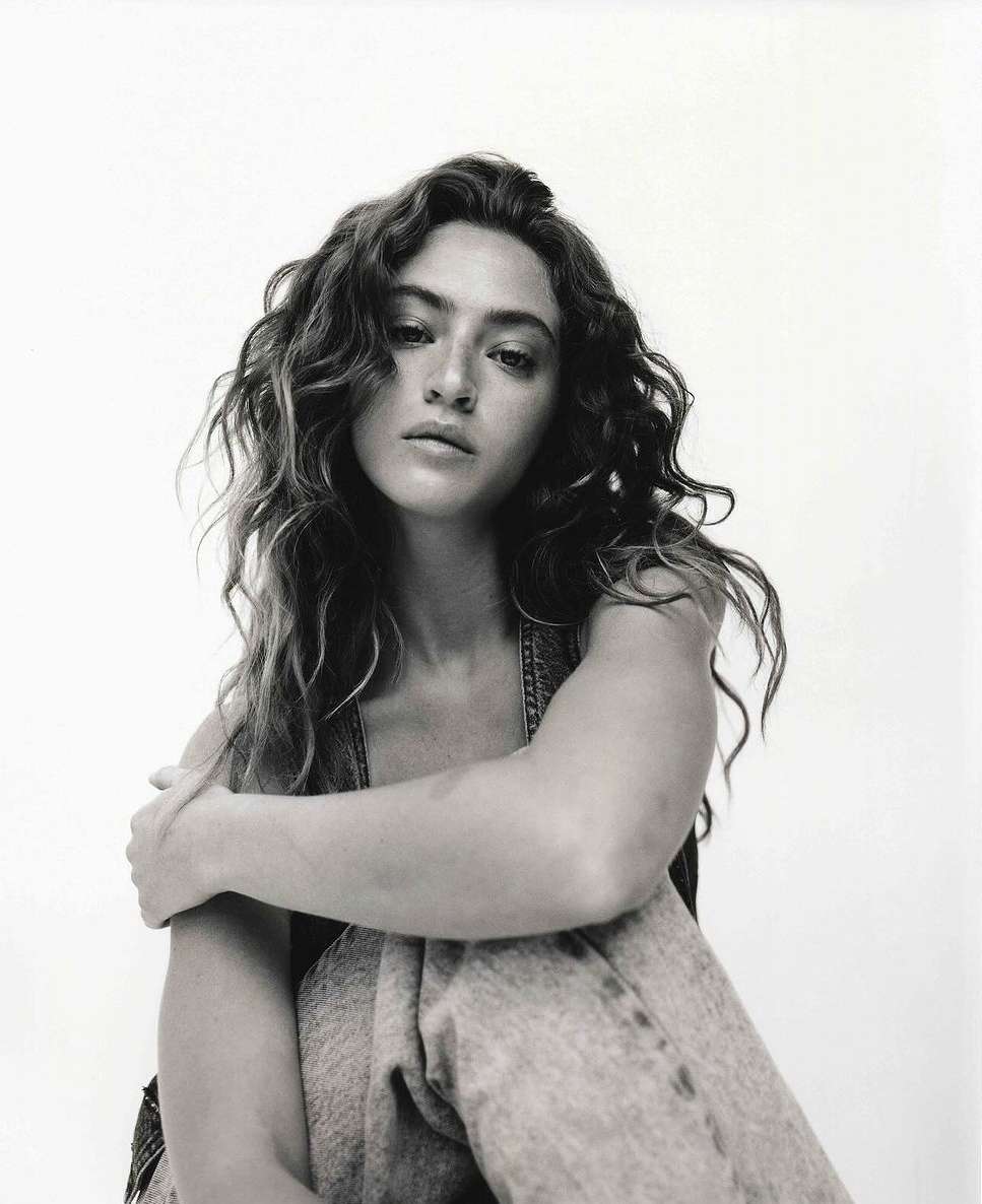 Portrait of a woman with long curly hair posing against a light background, photographed by Jon Stars in Los Angeles.