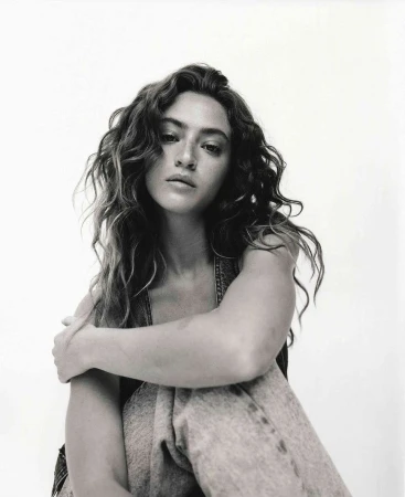 Portrait of a woman with long curly hair posing against a light background, photographed by Jon Stars in Los Angeles.