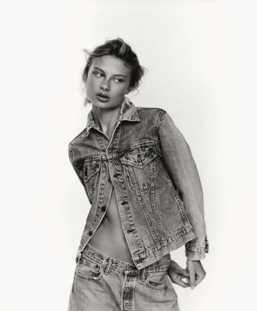Monochrome portrait of a woman wearing a denim jacket and jeans against a plain white background