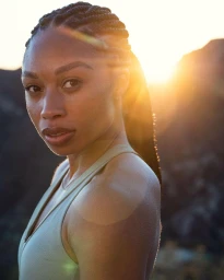 Portrait of a Black woman with braided hair wearing an athletic top outdoors at sunset by photographer Jon W Johnson