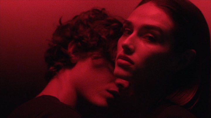 Close-up portrait of a man and a woman bathed in deep red light, captured by photographer Jonas Bresnan.
