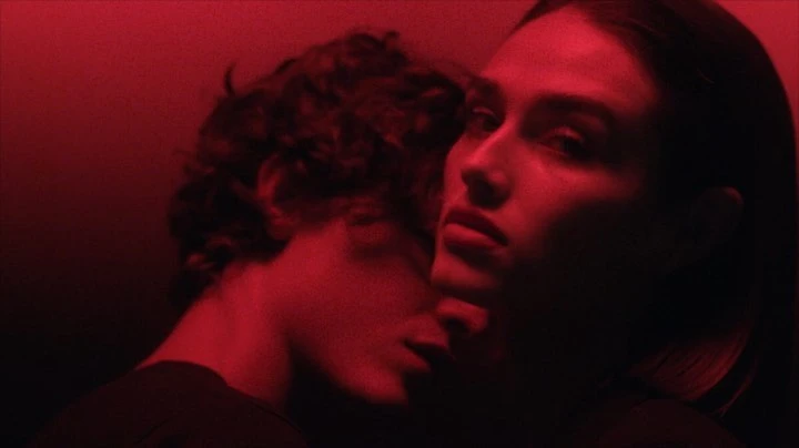 Close-up portrait of a man and a woman bathed in deep red light, captured by photographer Jonas Bresnan.