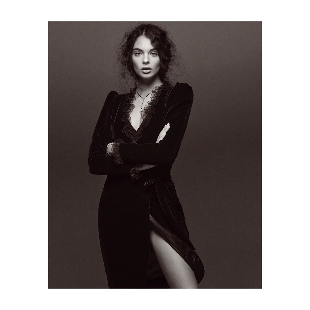 Portrait of a woman with dark wavy hair wearing a black velvet dress with lace trim, photographed by Jonas Bresnan.
