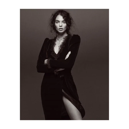 Portrait of a woman with dark wavy hair wearing a black velvet dress with lace trim, photographed by Jonas Bresnan.