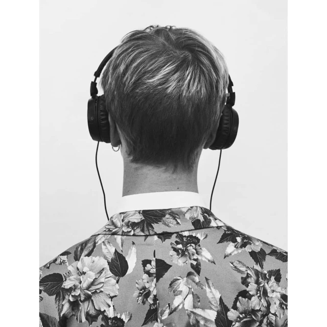 Back view of a person wearing headphones and a floral blazer against a white background. Head and shoulders shot, studio lighting.