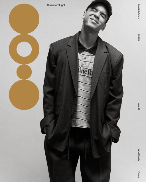 Young adult wearing a black blazer and baseball cap smiles slightly, posing against a light background with ochre graphic elements.
