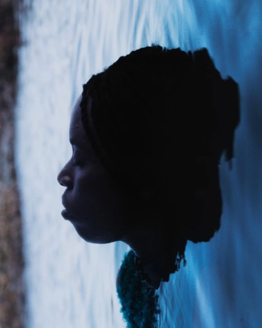 Profile portrait of an African American woman in water, with a textured shawl, captured in a dreamy and slightly surreal underwater setting.