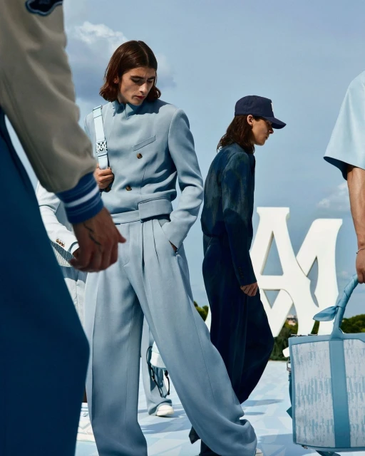 Fashion editorial image showcasing adult male models in light blue suits and caps in an outdoor setting with a clear sky.