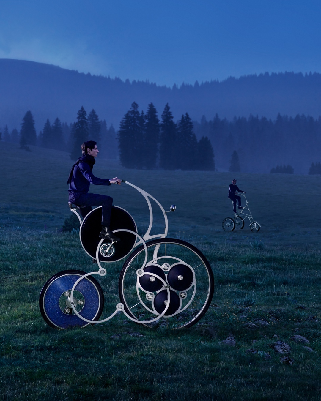 Whimsical bikes on a green field beneath a blue sky, featuring two adult males riding unique bicycles in a rural setting.