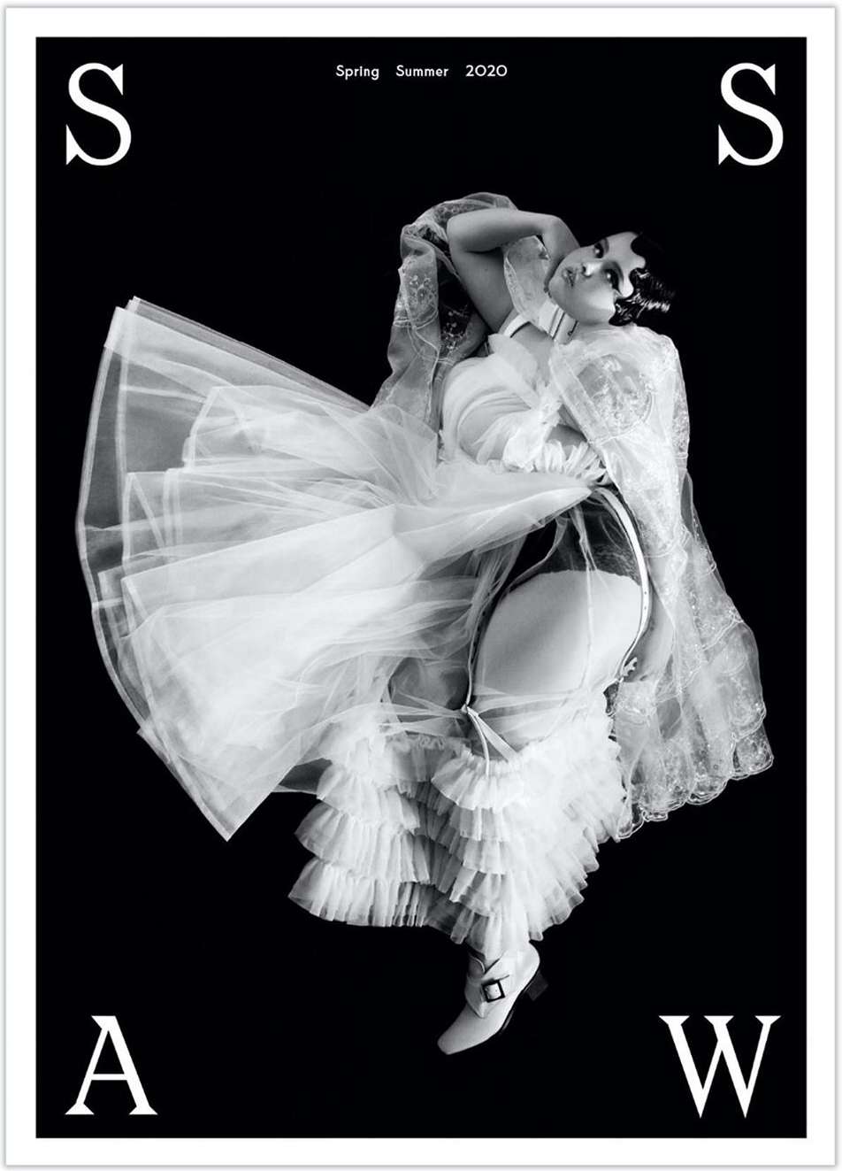 Black and white fashion shot featuring a woman in lingerie and a long, ruffled dress, with an 'S' and 'A' visible on the black background.