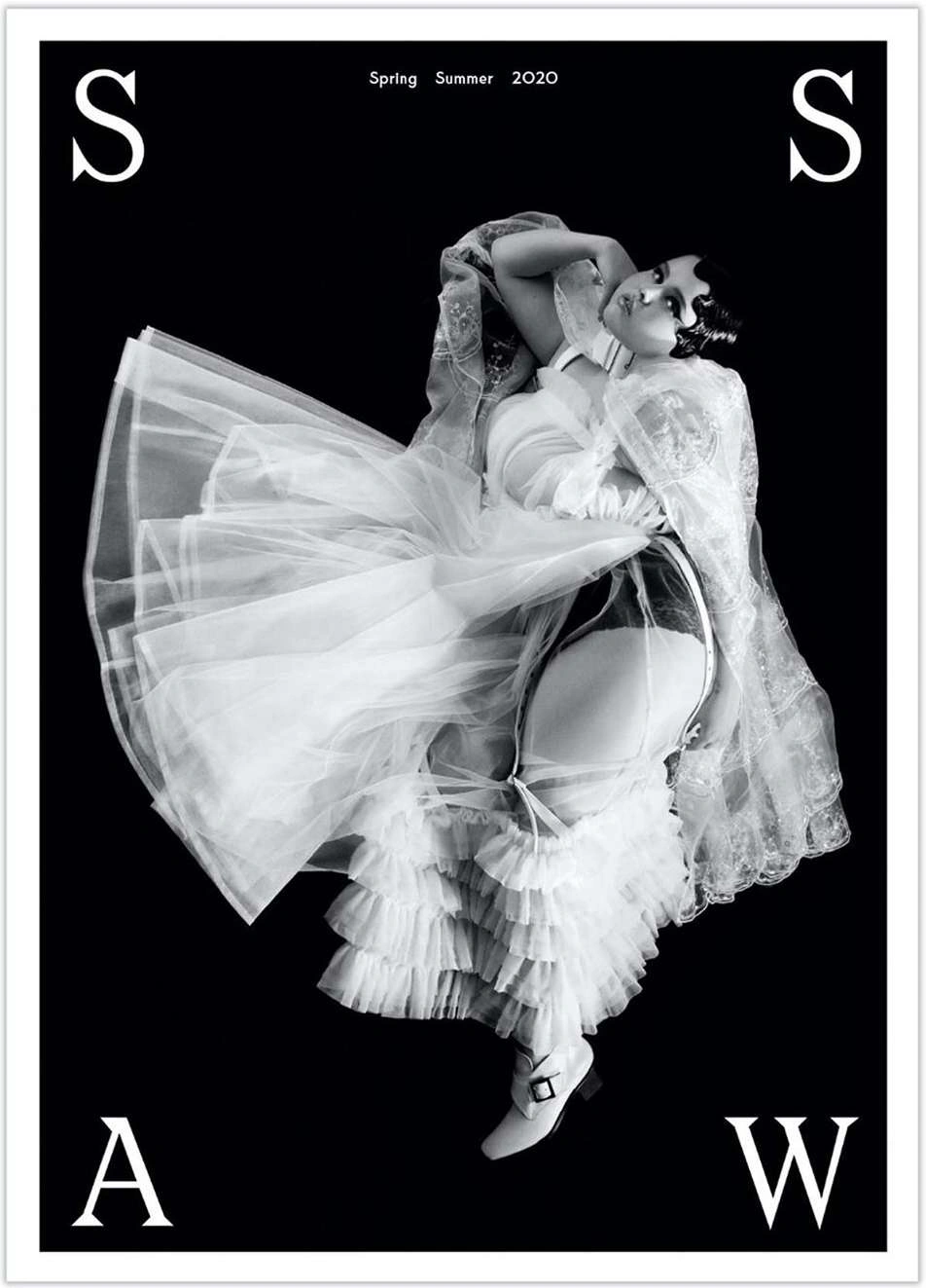 Model in voluminous white dress and sheer cape against a solid black background, directed by Jonas Lindstroem.
