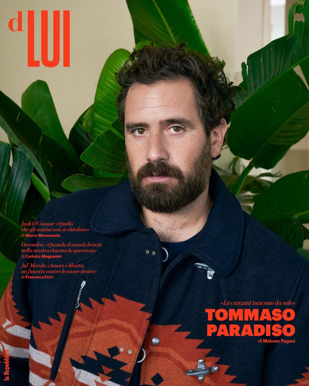 Magazine cover portrait of Tommaso Paradiso, Italian musician, wearing patterned jacket, with plant and magazine text in background.