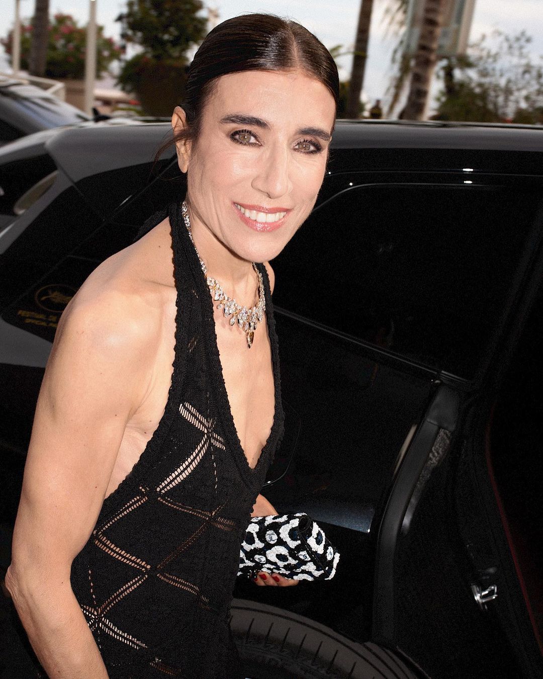 Woman in black halter dress and diamond necklace entering a car in Paris, captured by Jonas Unger.