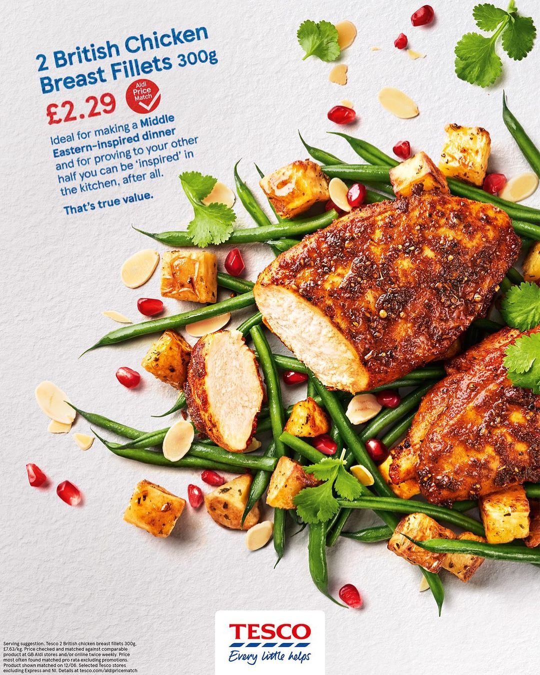 Overhead shot of seasoned chicken fillets surrounded by green beans, cubed potatoes, almond slices, and pomegranate seeds on a gray surface.