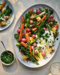 Roasted carrots, broccolini, radishes, and burrata on a large oval ceramic platter with herb dressing