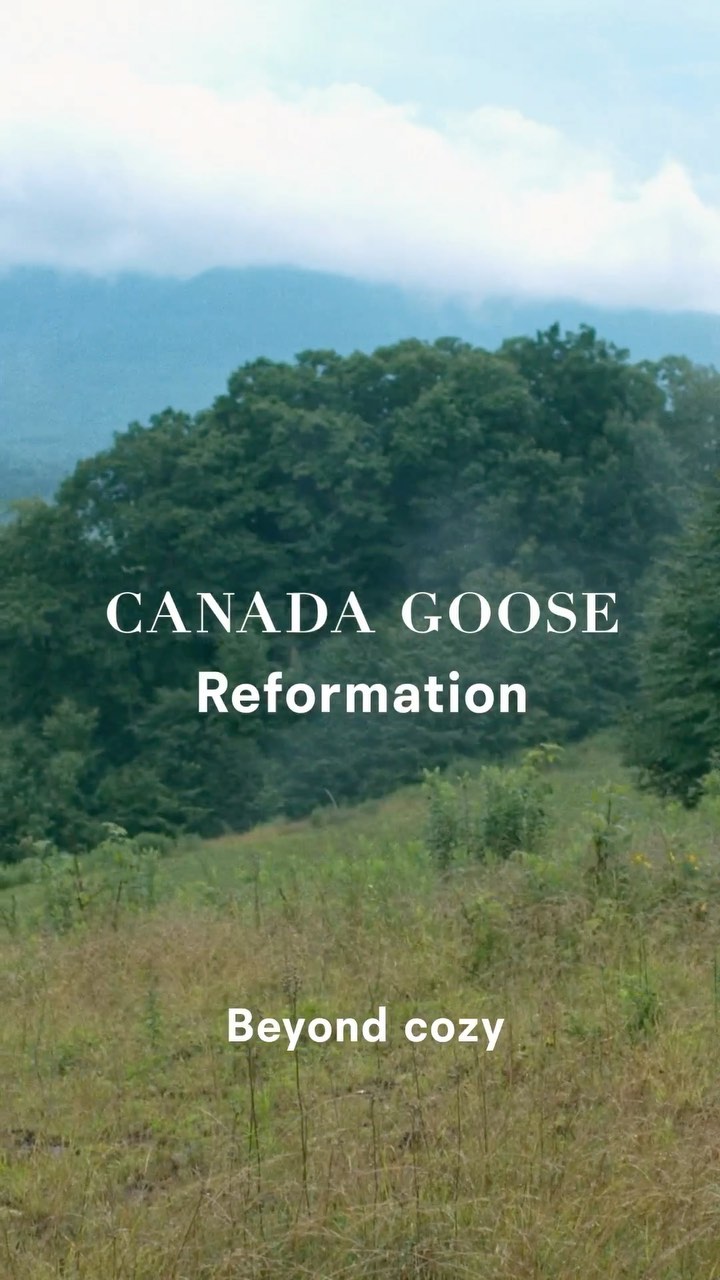 Scenic view of lush green hills and mountain range with Canada Goose and Reformation text overlay; clear sky and natural light.