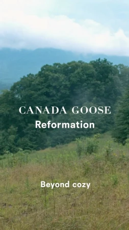 Scenic view of lush green hills and mountain range with Canada Goose and Reformation text overlay; clear sky and natural light.