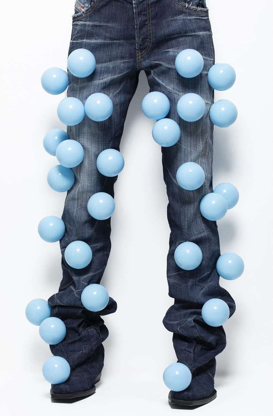 Fashion shot of denim jeans with light blue spheres attached, studio lighting, and a white background. Clothing and object-focused.