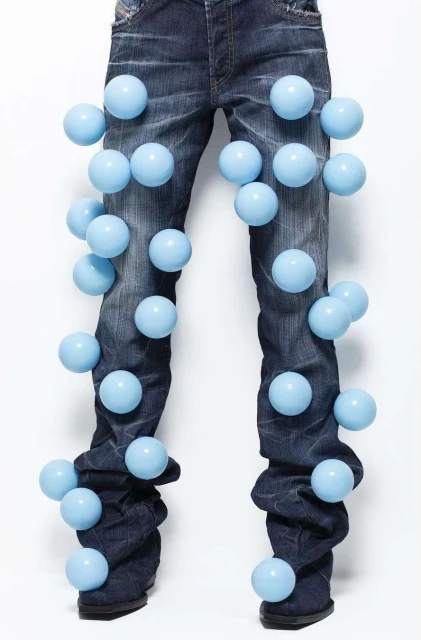 Fashion shot of denim jeans with light blue spheres attached, studio lighting, and a white background. Clothing and object-focused.