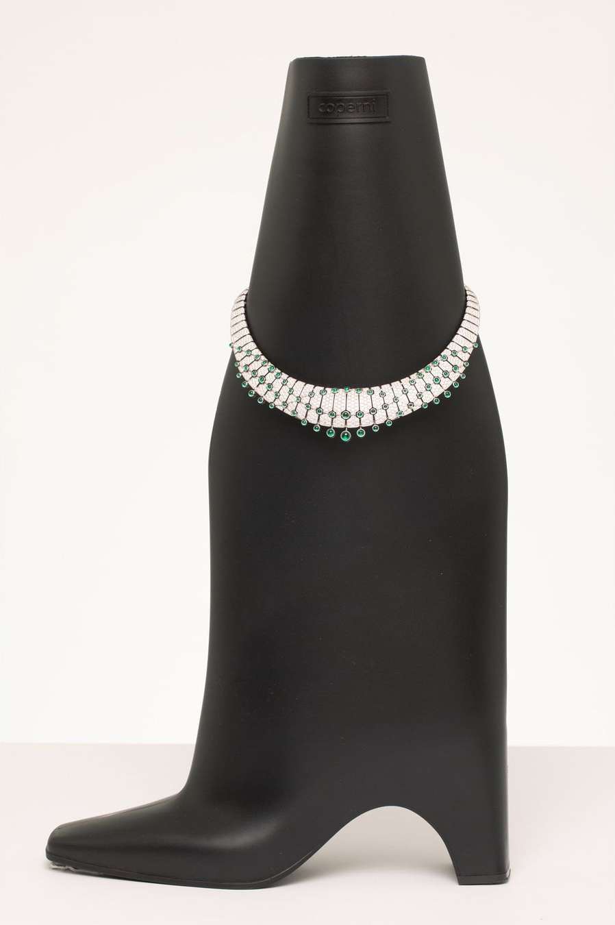 Necklace with green stones and diamonds on a black display bust against a white background in a studio setting. Jewelry concept.