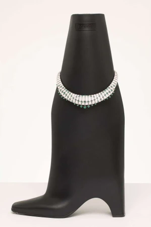 Necklace with green stones and diamonds on a black display bust against a white background in a studio setting. Jewelry concept.