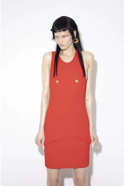 Fashion model in a red dress poses in a studio with a white background. The portrait features a short dress and striking makeup.