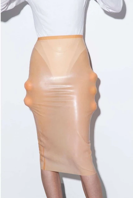 Model wearing a beige latex pencil skirt with spheres, paired with a white long-sleeved shirt against a bright white backdrop.