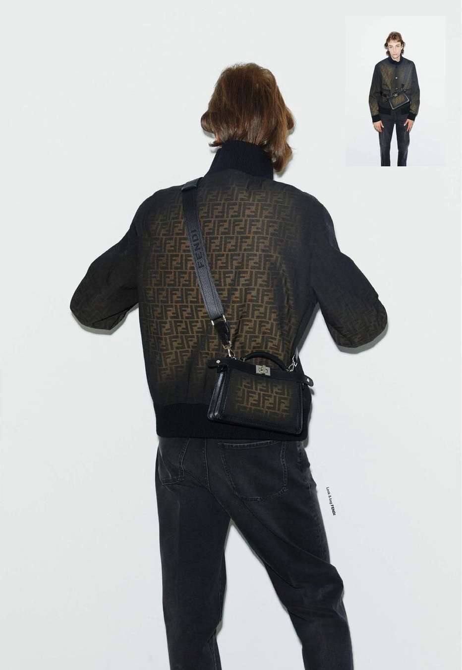Male fashion model poses in patterned jacket and dark jeans with Fendi purse and crossbody strap against a white background.