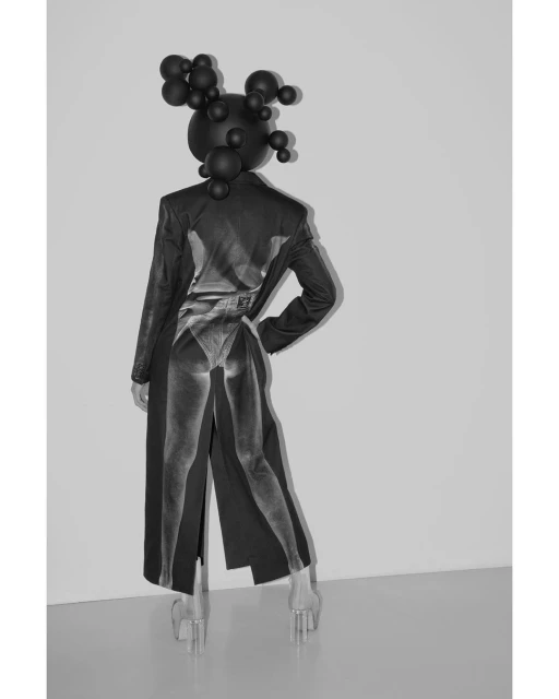 Artistic black and white studio shot of a person in a black outfit and sphere headpiece with a superimposed body on the clothing.