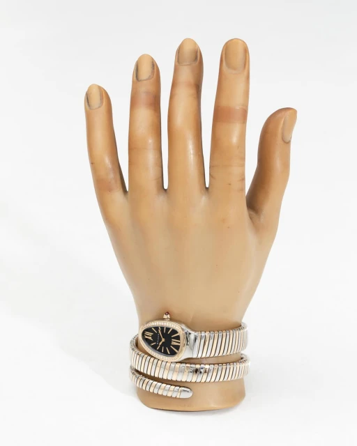 Wristwatch with a snake-inspired band wrapping around a mannequin hand against a white backdrop in a studio-lit setting.