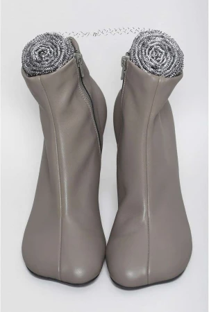 Two grey ankle boots are displayed side by side against a white backdrop, with a stainless steel scouring pad placed inside each boot.