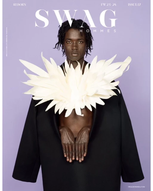Editorial fashion shot of a Black man in a black coat and ornate white collar against a light purple background for SWAG Hommes magazine.