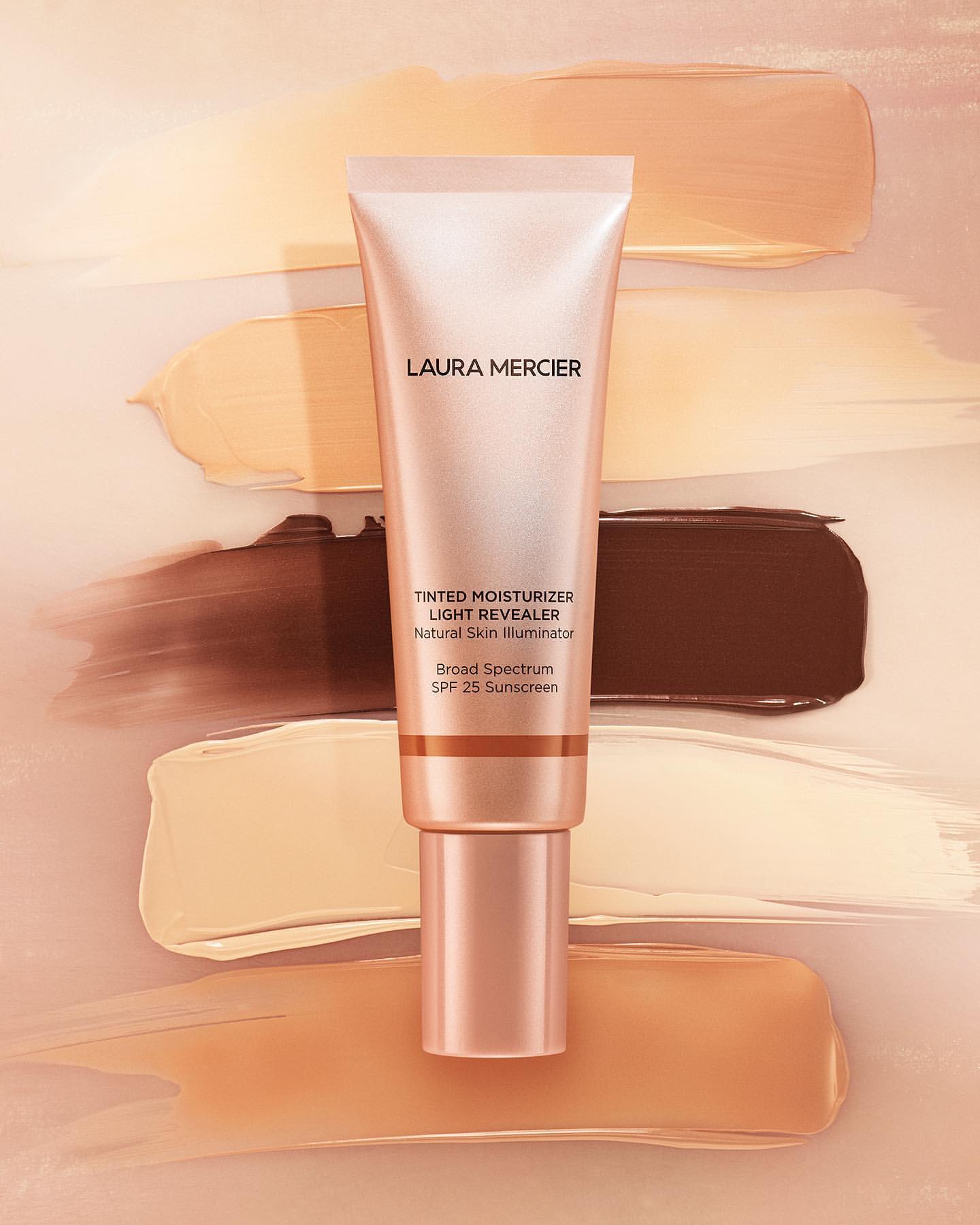 Laura Mercier tinted moisturizer tube on background of foundation swatches in neutral and brown tones, studio shot for Beauty.