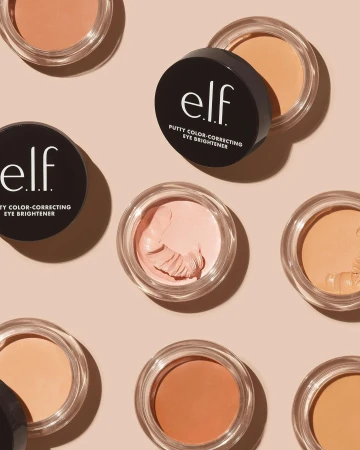 Eye brightener product display with several containers of ELF putty color-correcting cream arranged on a light pink background.