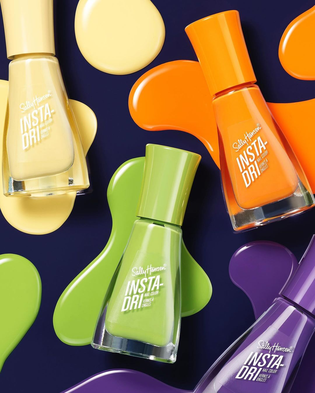 Eye-level close-up showcases yellow, green, orange, and purple Sally Hansen Insta-Dri nail polish bottles with matching color smears on a dark backdrop.