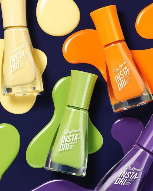 Eye-level close-up showcases yellow, green, orange, and purple Sally Hansen Insta-Dri nail polish bottles with matching color smears on a dark backdrop.