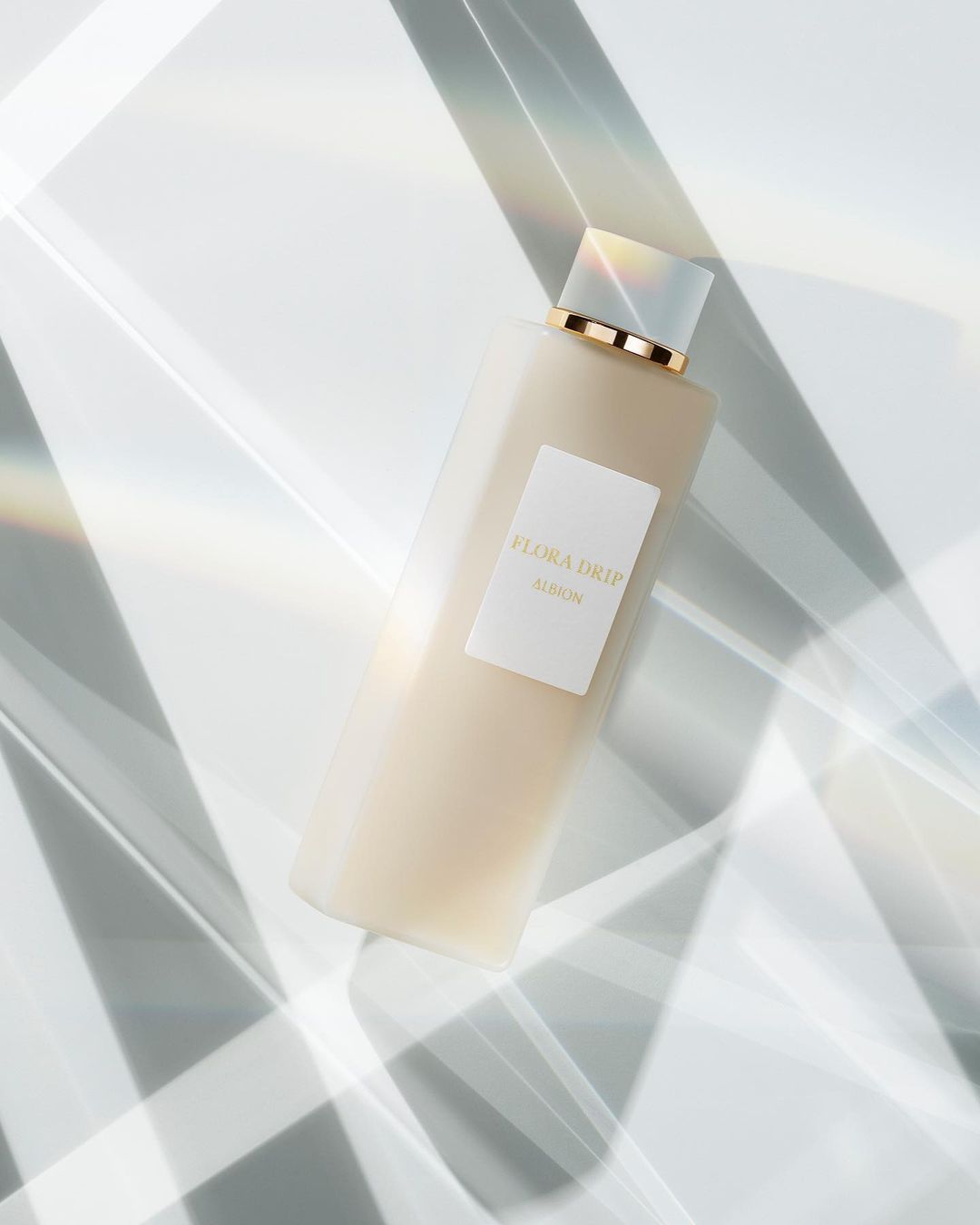 Still life product shot featuring a bottle of Flora Drip Elaskin skincare product, showcasing minimalist aesthetic and geometric light.