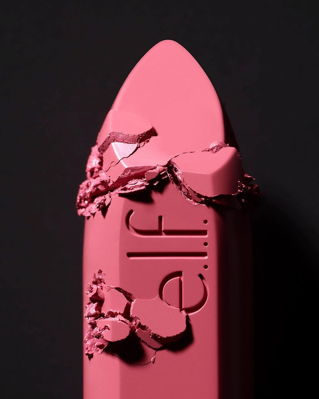 Macro shot of a pink e.l.f. lipstick with a textured surface and the brand logo against a dark background. Beauty product.