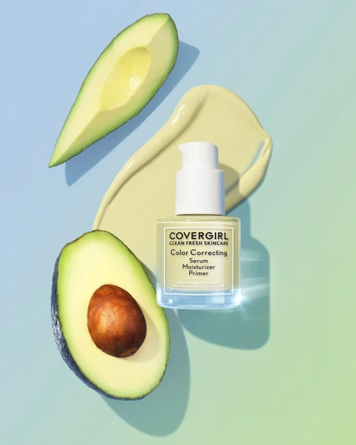 CoverGirl Color Correcting Serum Moisturizer Primer photographed with avocado halves on a gradient blue to yellow background.