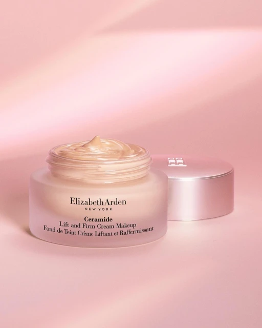 Elizabeth Arden Ceramide Lift and Firm Cream Makeup jar with product shown on a pink backdrop with the lid to the right.