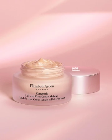 Elizabeth Arden Ceramide Lift and Firm Cream Makeup jar with product shown on a pink backdrop with the lid to the right.