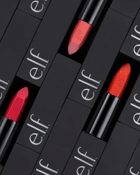 Overhead arrangement of black lipstick tubes with white e.l.f. branding and colorful cosmetic bullets against a dark surface.