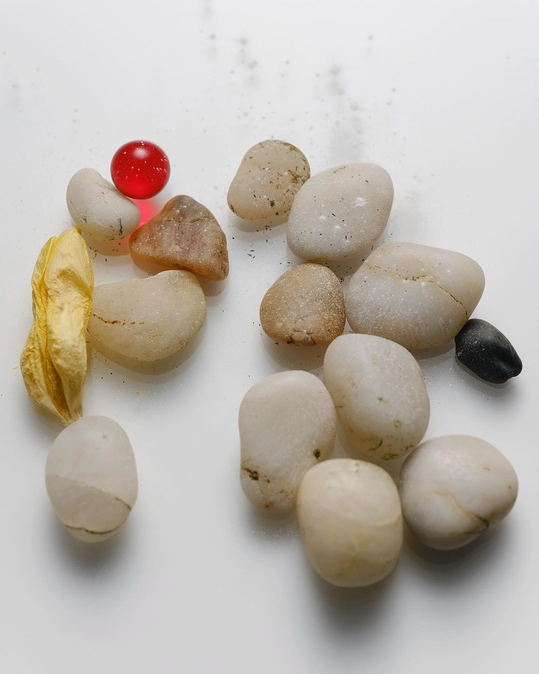 Close-up of colorful pebbles and decorative gem stones on a white surface showcasing variety in color and texture.