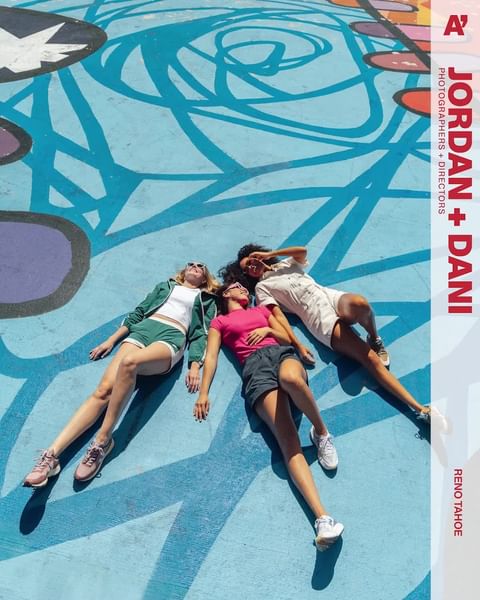 Three women in summer clothing lying on their backs on a sunny, colorful patterned concrete surface in Reno Tahoe, captured from an overhead angle.