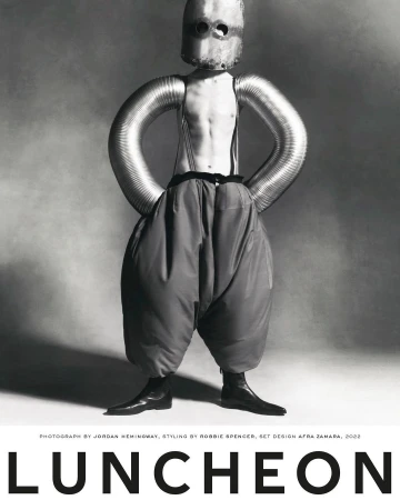 Artistic black and white studio portrait of a person with metallic headgear and tubing, paired with oversized trousers and boots.