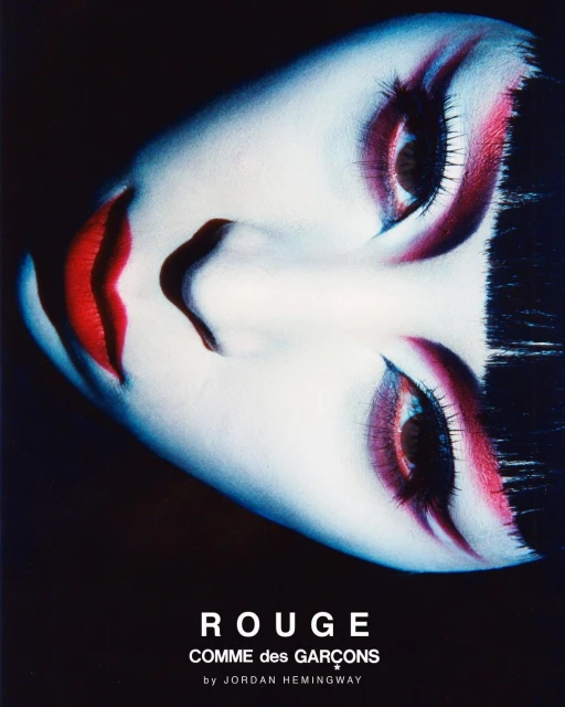 Dramatic close-up portrait of a woman with bold red makeup and dark hair against a black background, beauty and cosmetics focus.