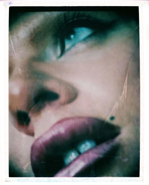 Close-up portrait of a woman's face featuring blue eyes, full lips, and fair skin, set against a blurred, abstract backdrop.