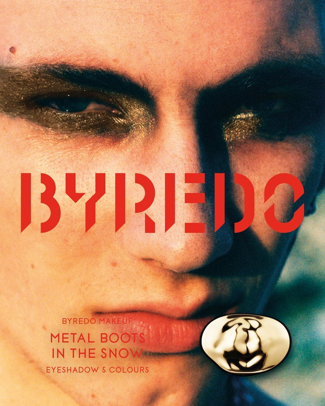Close-up of a person's face with bold gold eyeshadow, accompanied by the logo and product name, "BYREDO METAL BOOTS IN THE SNOW."