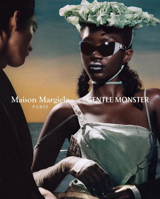 Eye-level shot of two models. A woman wears light-green clothing, sunglasses, and a sculptural hat. Text reads Maison Margiela x Gentle Monster.