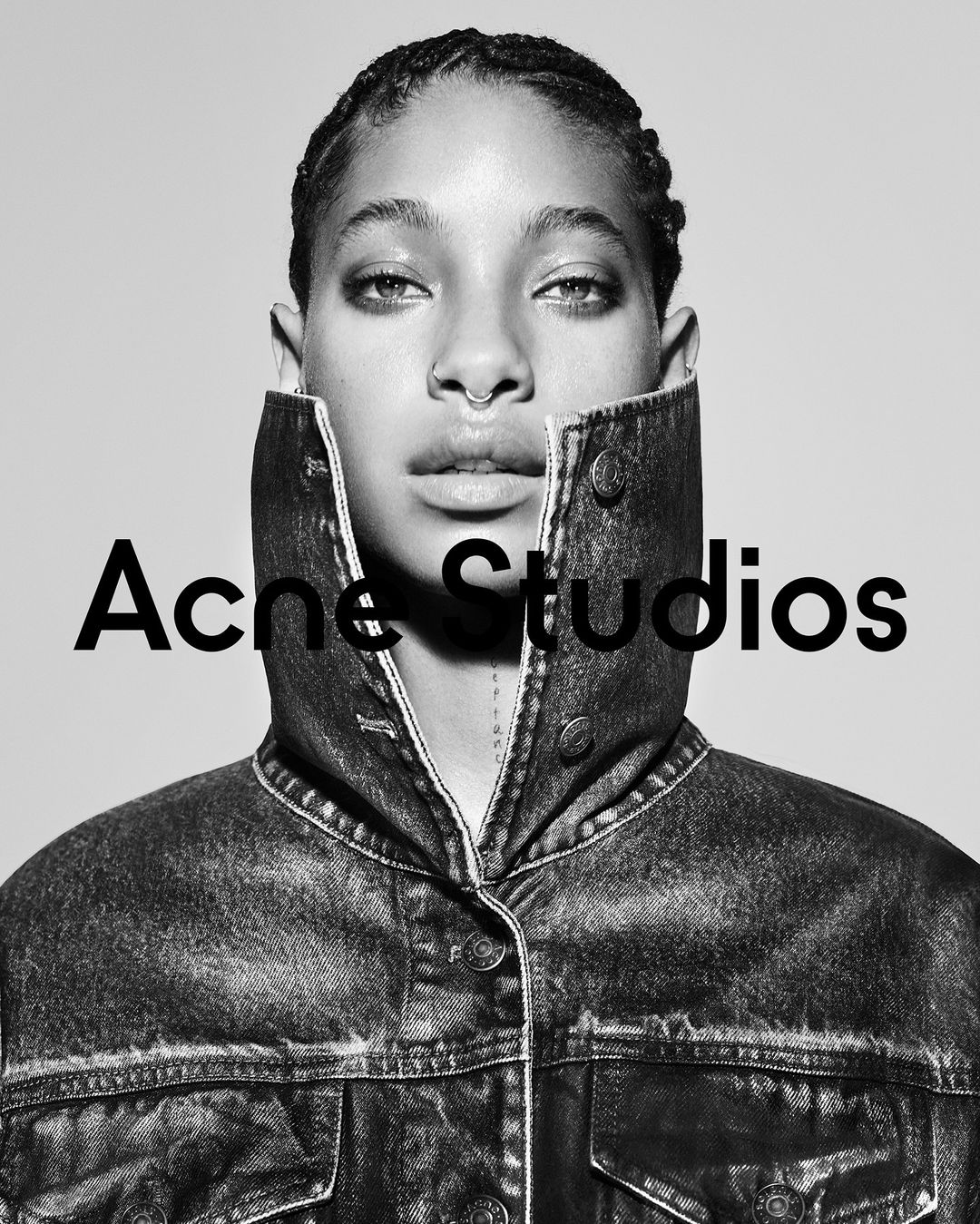 Black-and-white portrait of a woman in a denim jacket, facing forward against a neutral background, with the 'Acne Studios' logo.